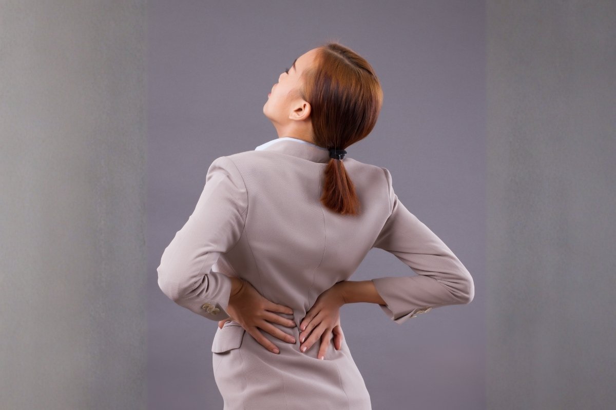 Woman holding her lower back in pain, a common symptom of a slipped or herniated disc