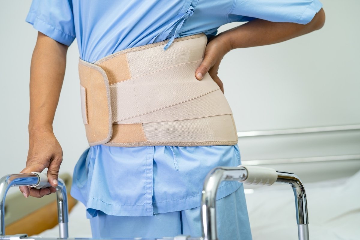 Patient wearing a spinal brace and using a walking frame while recovering from a spinal fracture at Sama Hospital, South Delhi